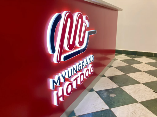 Svítící 3d logo myungrang hotdog vystupující z barvového pultu